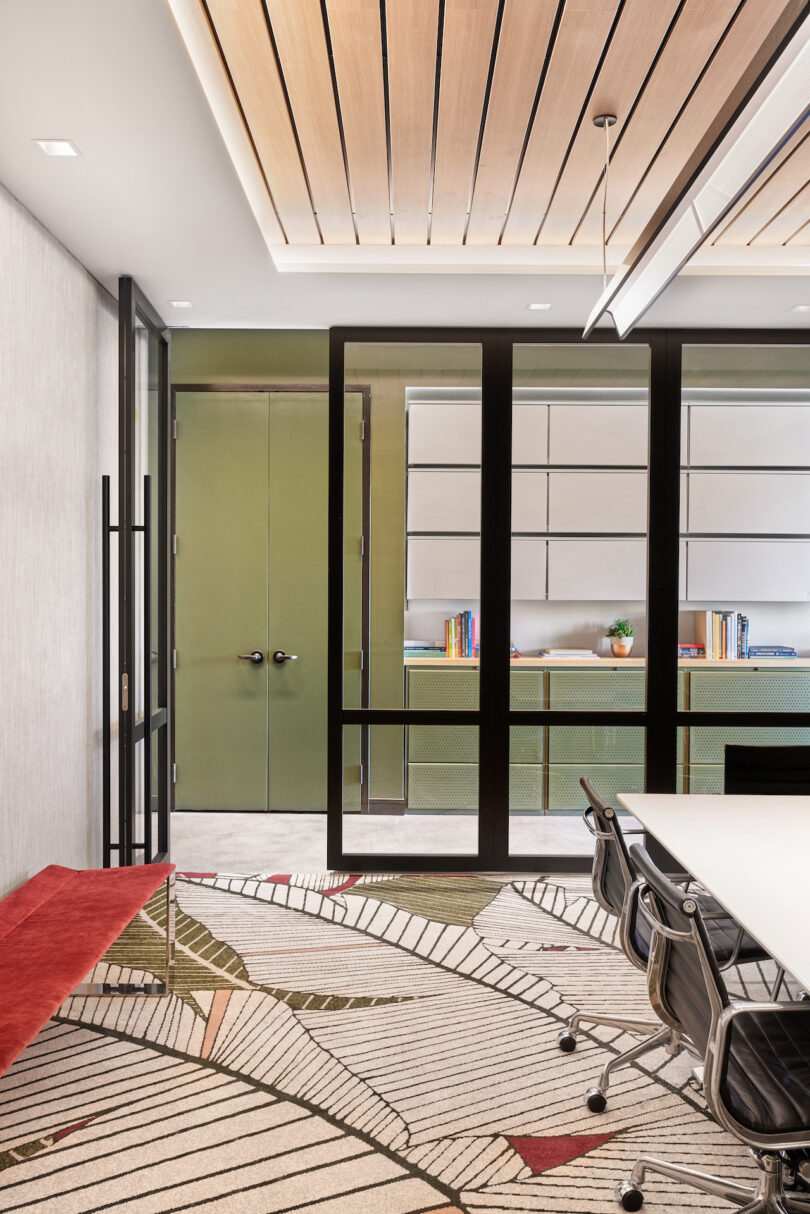 Modern office meeting room with a white table, black chairs, patterned carpet, and frosted glass partitions. wooden slatted ceiling with integrated lighting