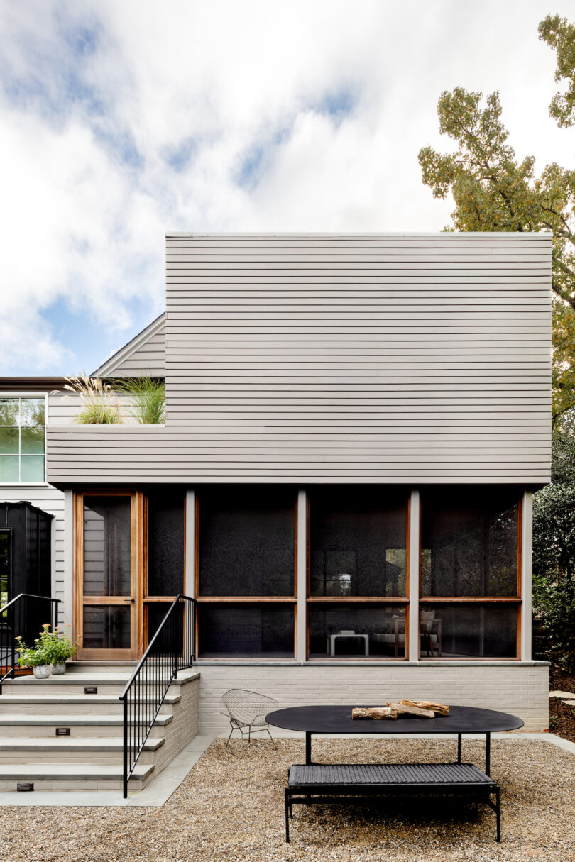 back of modern home with stairway and black outdoor dining table