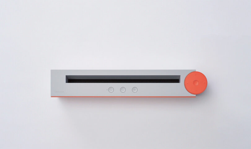 A top view of the Vibrary Digital LP Player with a minimalist design featuring a gray body and contrasting orange dial.