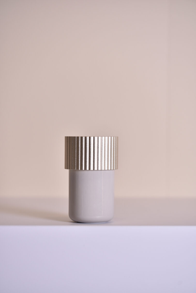 a storage box bathroom accessory with a gold cap on a grey table