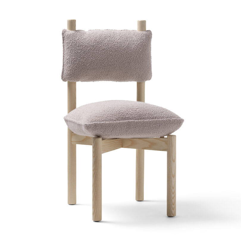 A modern wooden chair with fluffy beige upholstery on both the seat and backrest, isolated on a white background.