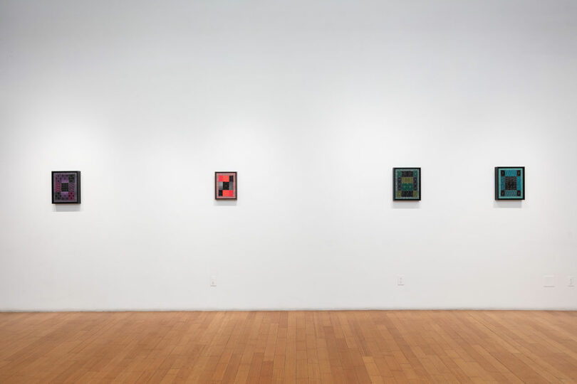Four colorful abstract paintings displayed on a white gallery wall with a hardwood floor.