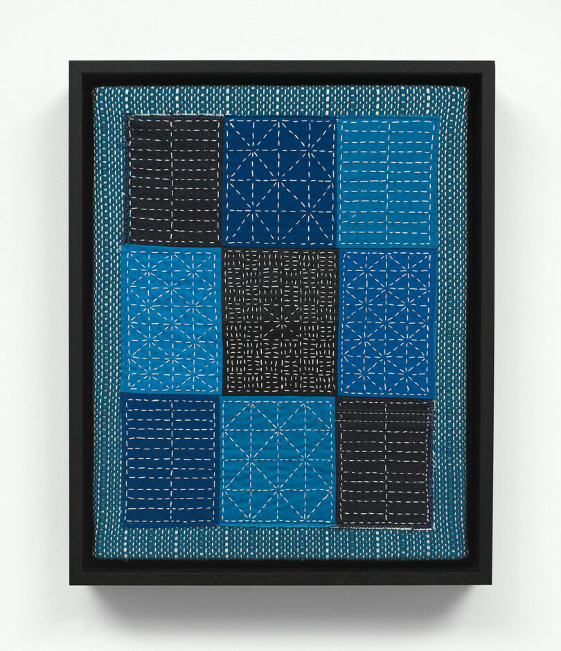 Framed artwork featuring a geometric pattern of white lines forming various intricate designs on a dark blue background, displayed in a black frame.