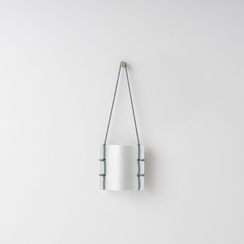 ceramic vase hanging on a white wall by a thread