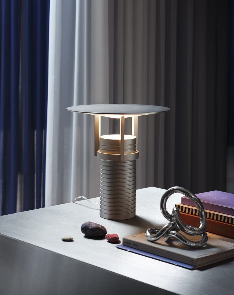 Modern adjustable metal table lamp with a cylindrical base, showcased on a styled surface.