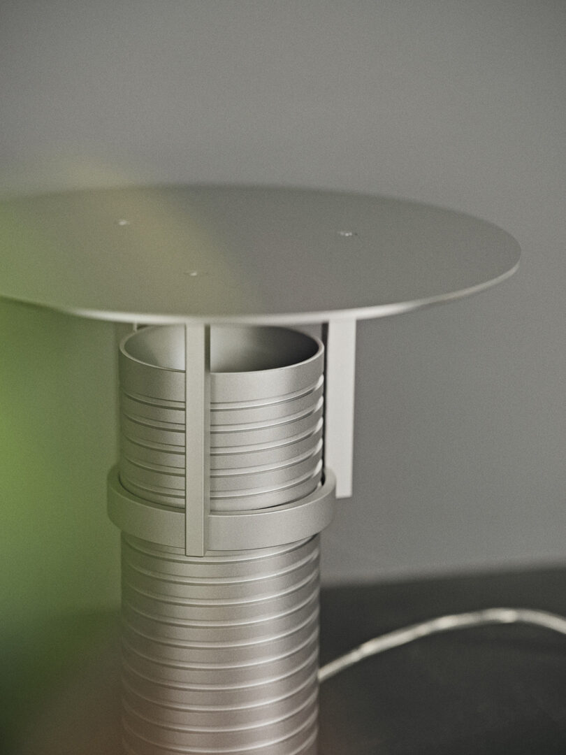 Modern adjustable metal table lamp with a cylindrical base, showcased on a styled surface.