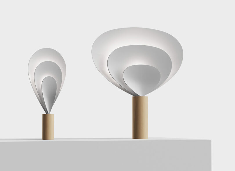 SWNA's Drop Light in small and large sizes, each design comprised of three parabolic forms gathered into a fan-like shape nested into one another and held together by a cylindrical wood base.