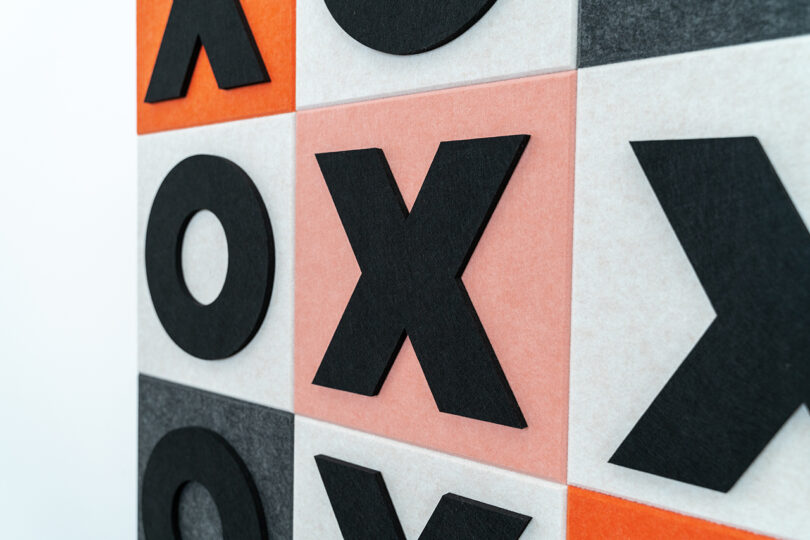 light pink, orange, white, and dark grey felt tic tac toe wall game