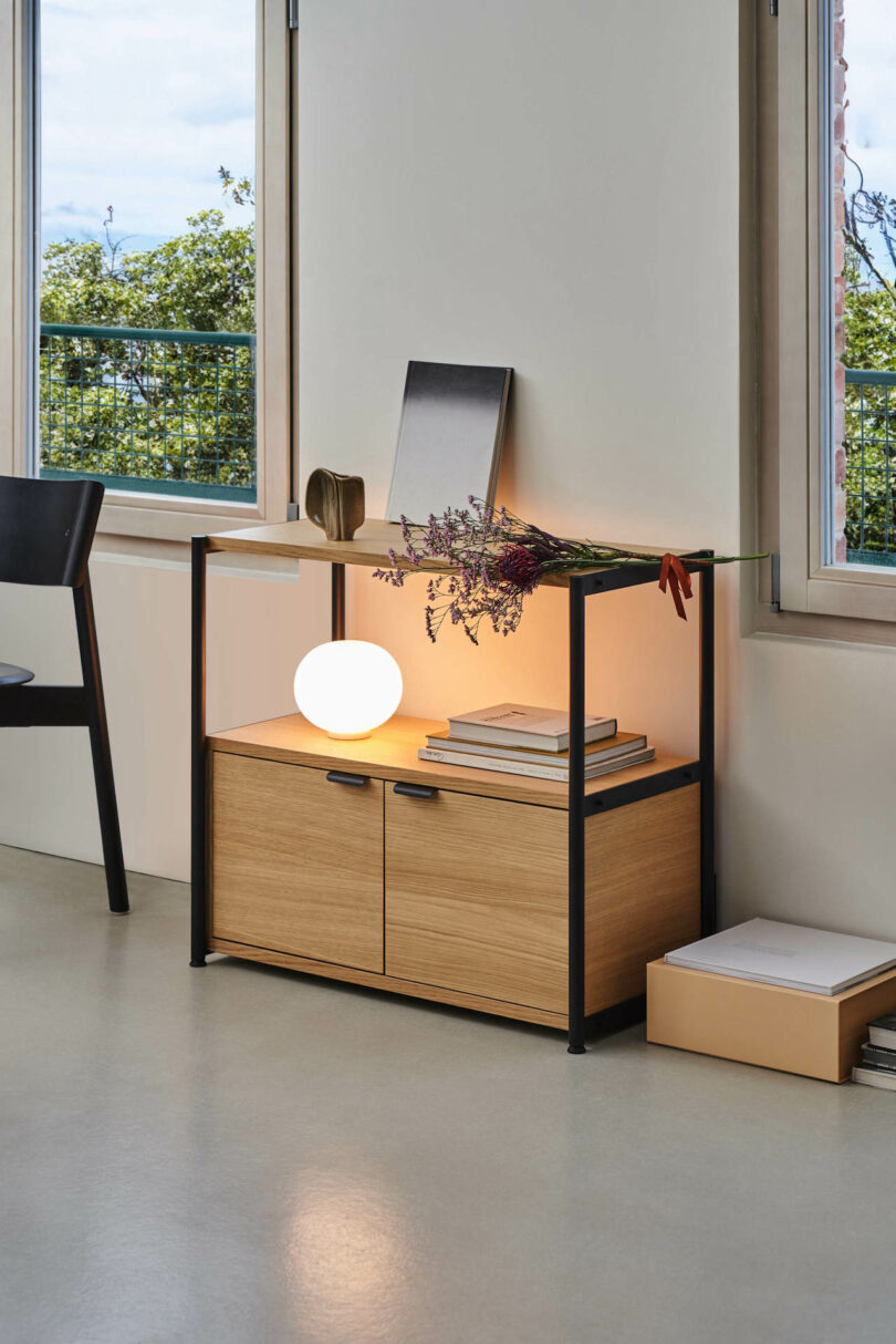 lamp glowing on a console table between two windows