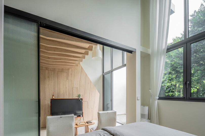 view from small modern bedroom looking out through sliding gladd doors into living room