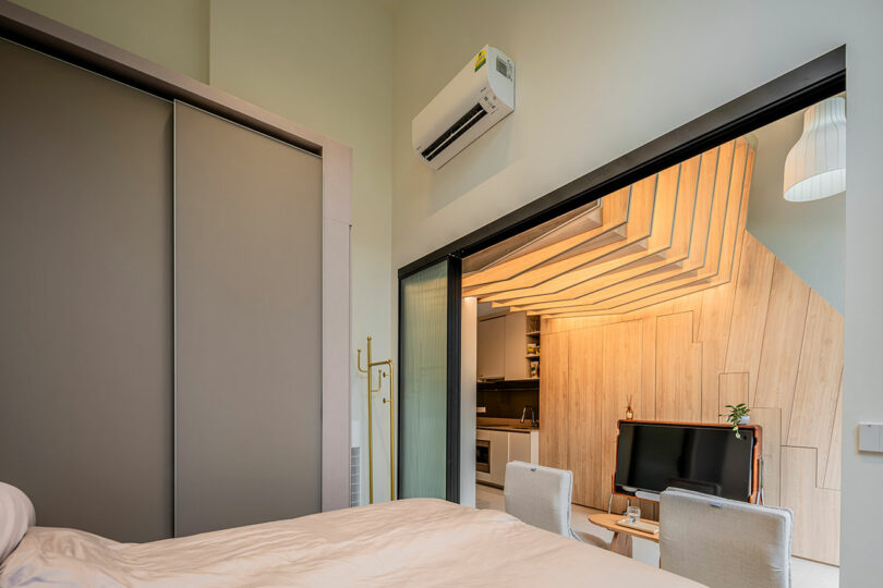 view from small bedroom looking out through sliding glass doors to small living room with embedded lights in ceiling