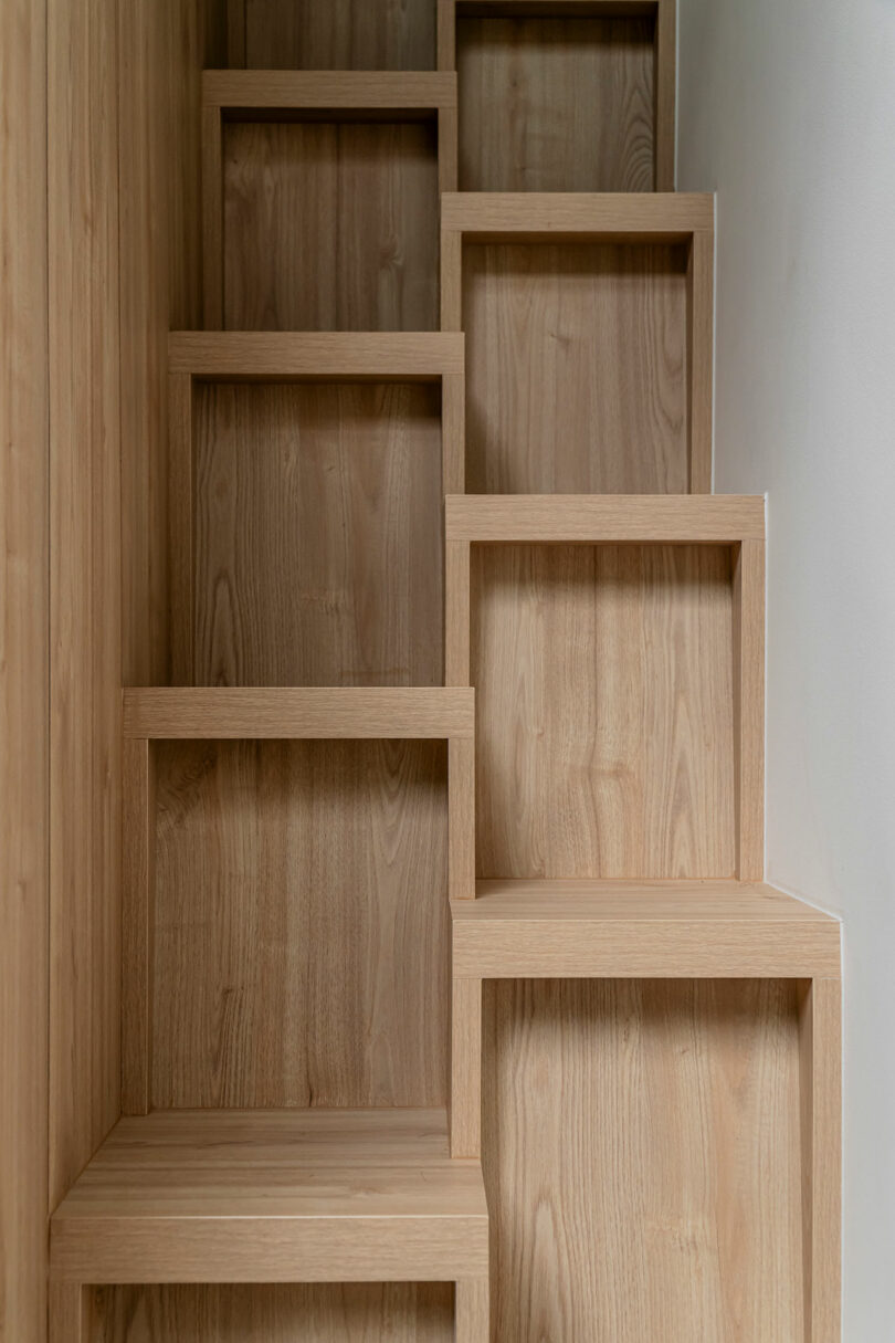 Wooden staircase with cube-shaped steps against a white wall in a modern interior.