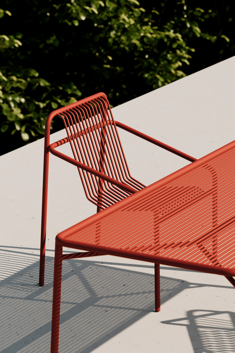 Modern red outdoor furniture casting shadows in sunlight.